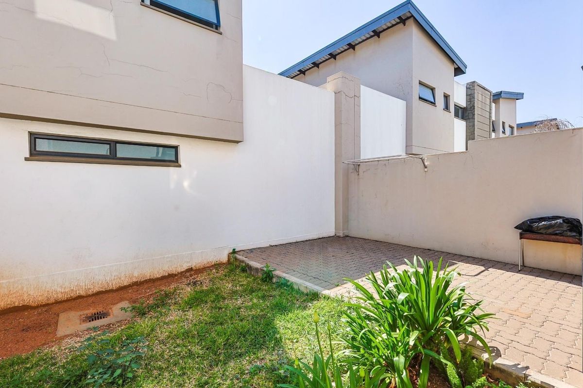 A private rear courtyard area featuring paved flooring, a small grass patch, and high boundary walls for privacy.