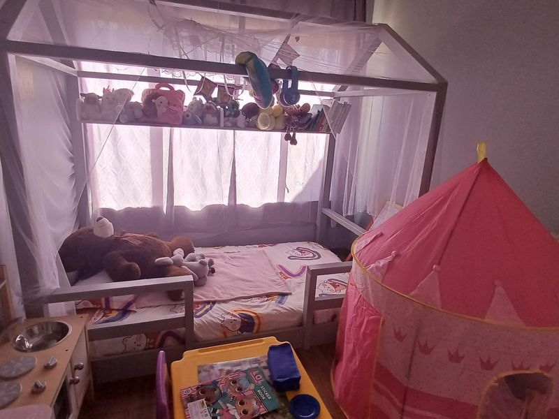 A child's bedroom featuring a house-style bed frame and window treatments.