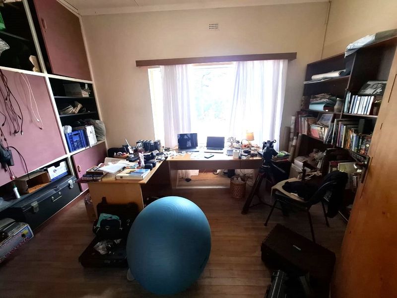 A functional home office space featuring built-in storage shelving and laminate flooring, offering a quiet area for work or study.
