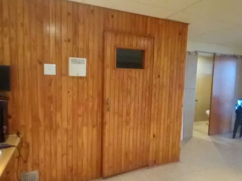 A dedicated sauna room featuring timber wall paneling, tiled flooring, and direct access to an adjacent area through a sliding glass door.