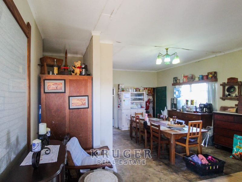 Open plan living and dining area featuring original ceiling finishes and flooring, offering a spacious layout with potential for modernization.