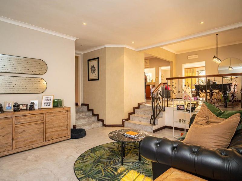 Spacious open-plan living area featuring stone stairs, wrought iron balustrades, and an exposed brick feature wall, creating a warm and inviting multi-level layout.