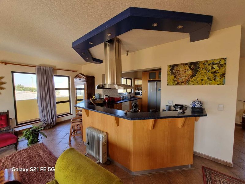 Open plan kitchen featuring a breakfast bar, stainless steel extractor fan, and built-in cabinetry, seamlessly integrated with the living area.