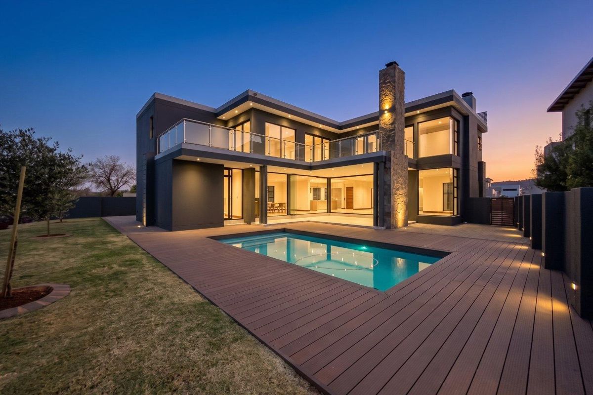 Modern double-story residence featuring a swimming pool, expansive composite decking, stone-clad chimney, and large glass sliding doors opening to the rear garden.