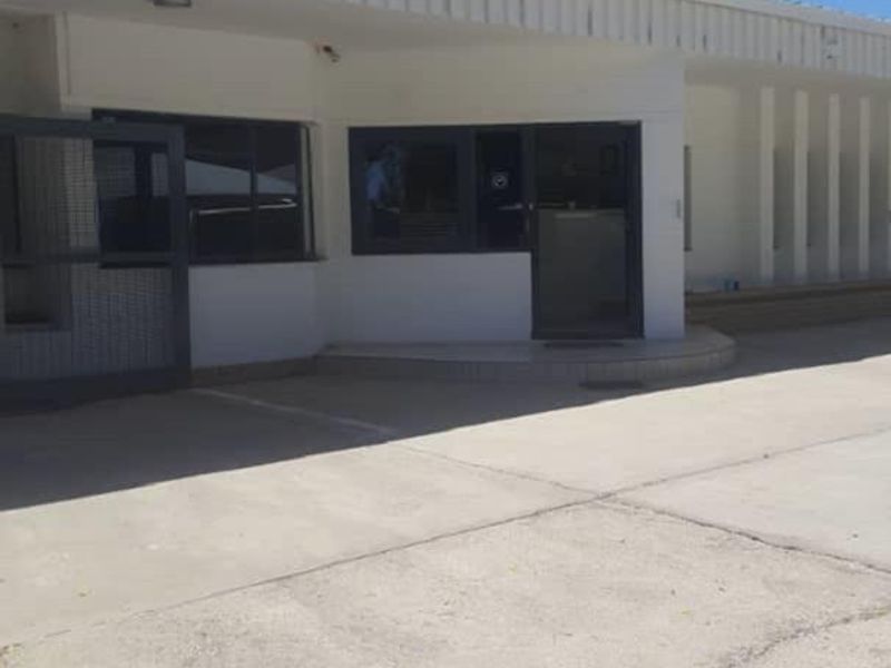 Front exterior view of the office building featuring a concrete driveway, metal security gate, and aluminum-framed windows under a covered entrance.