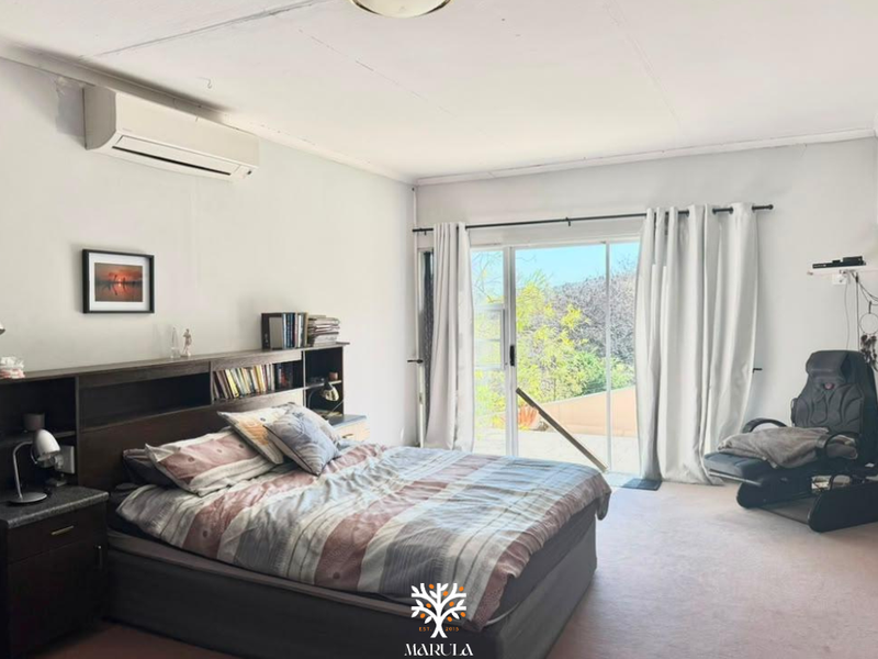 Spacious bedroom featuring a split-system air conditioner and large sliding glass doors that provide natural light and access to the outdoors.