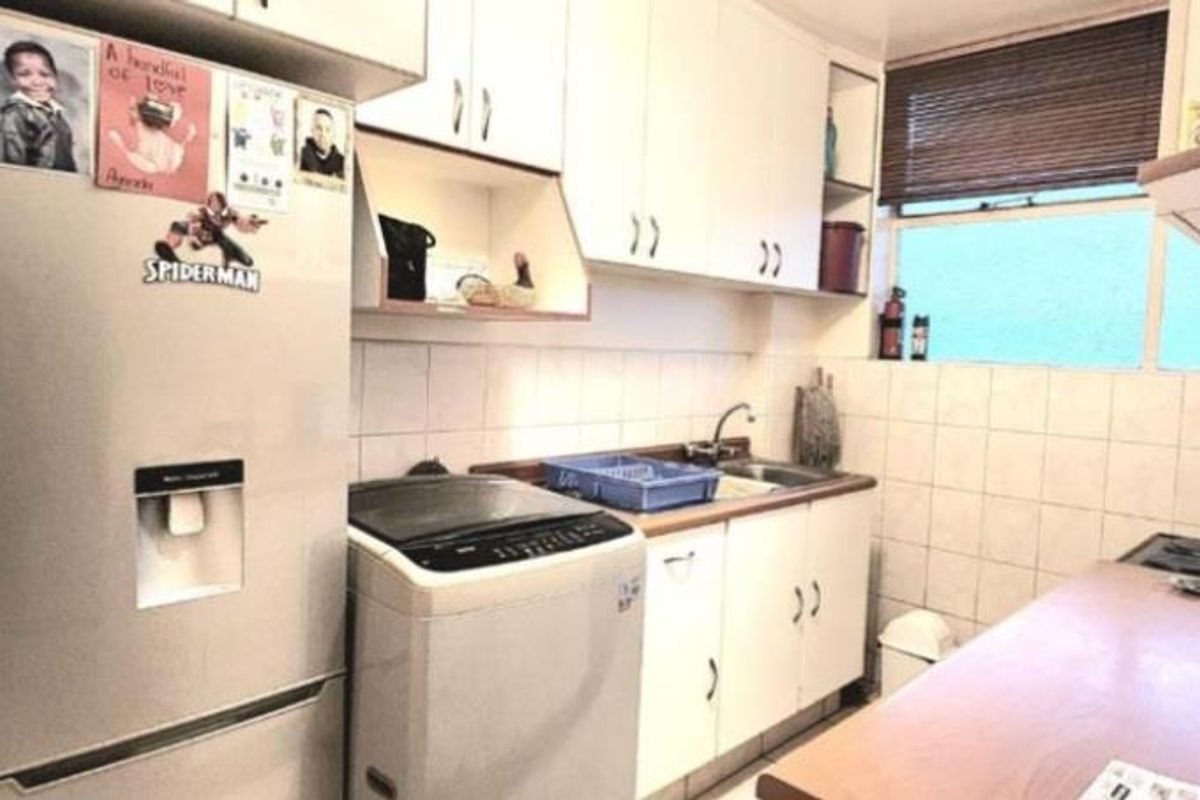 A functional kitchen featuring white cabinetry, a tiled splashback, and a dedicated space for laundry appliances.