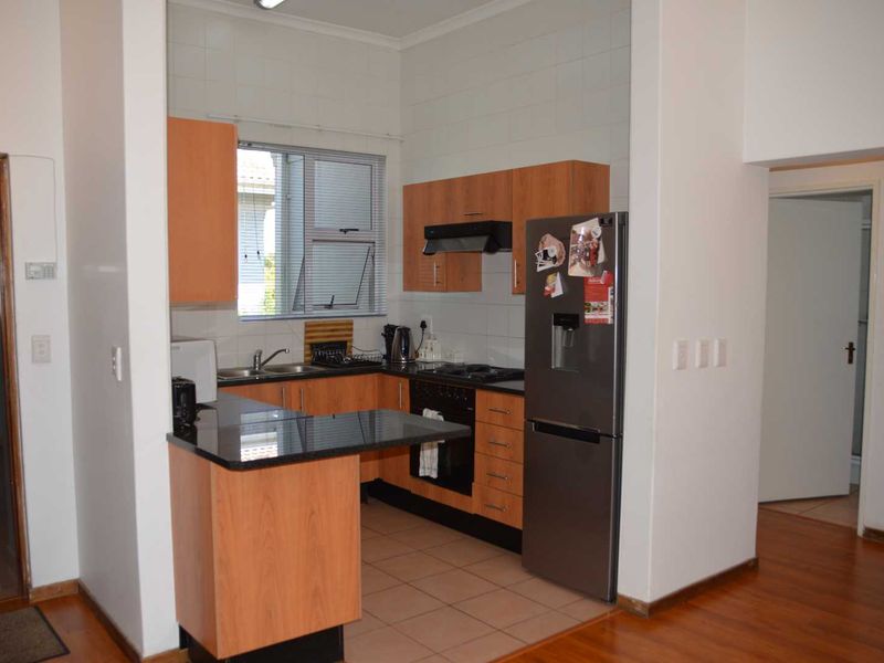 A functional kitchen featuring laminate cabinetry, granite countertops, a built-in oven with gas hob, and a tiled backsplash.