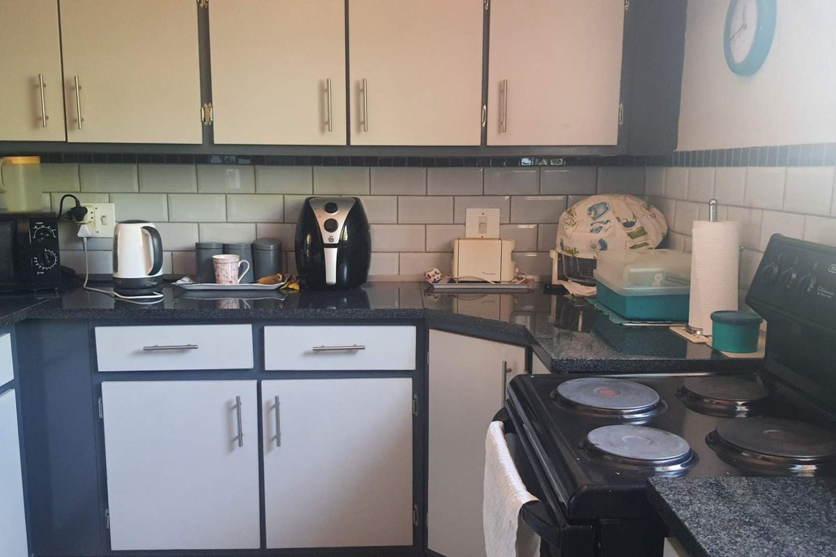 A functional kitchen featuring dark granite countertops, white cabinetry with modern handles, and a subway tile backsplash.