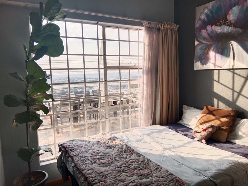 A bedroom featuring a large window with security bars, allowing natural light to enter the space.