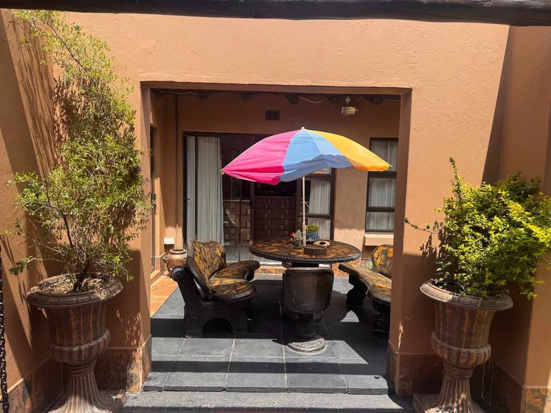 A covered patio area featuring tiled flooring and exposed timber beams, providing a sheltered outdoor space accessible through sliding glass doors.