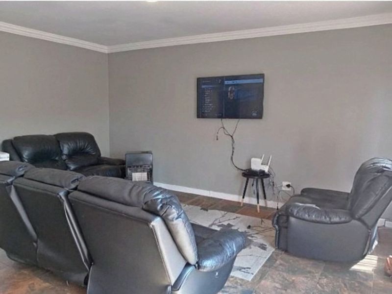A living room featuring tiled flooring and crown molding, currently set up as a lounge area.