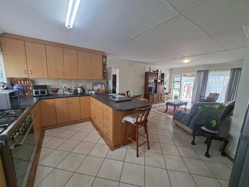 Open-plan kitchen and living area featuring laminate cabinetry, gas hob, tiled flooring, and direct access to an outdoor patio through sliding glass doors.
