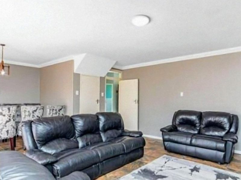 A living room area featuring tiled flooring, neutral wall tones, and coving, providing a functional space for relaxation.