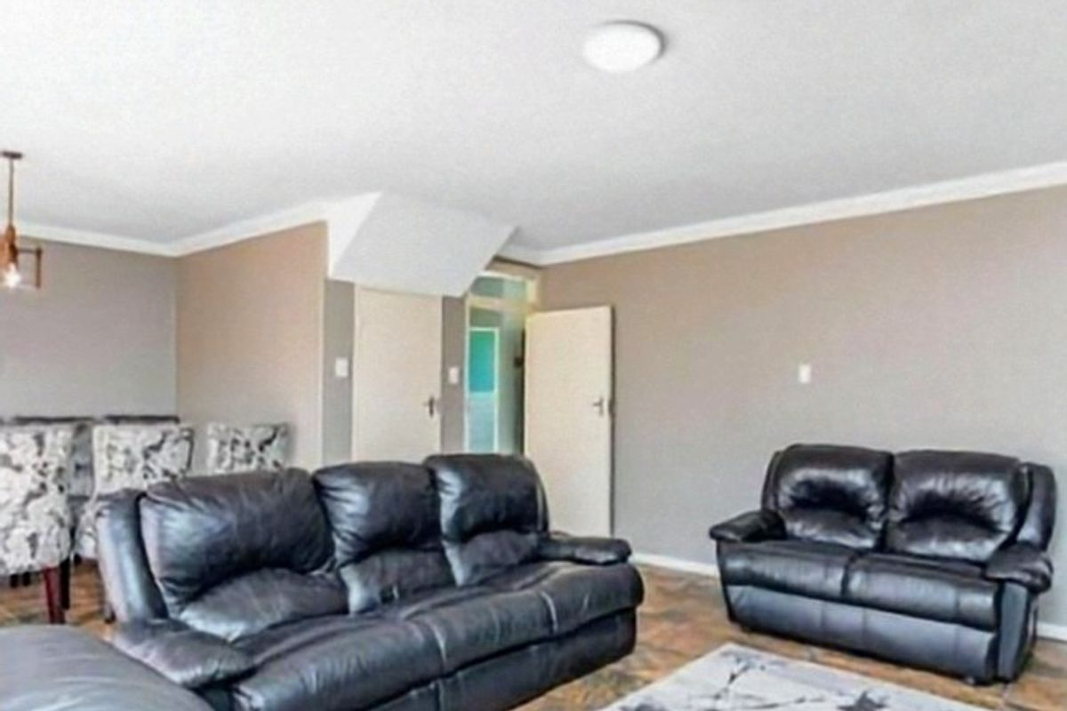 A living room area featuring tiled flooring, neutral wall tones, and coving, providing a functional space for relaxation.