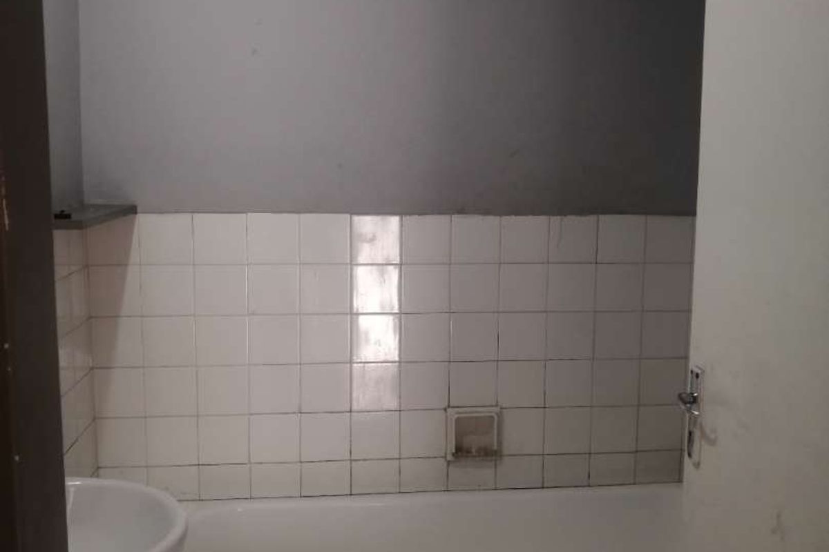 A functional bathroom featuring a standard bathtub with tiled splashback and a pedestal basin, requiring cosmetic updates to improve its overall condition.