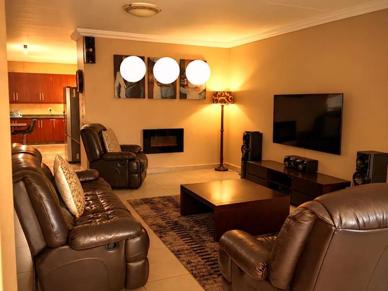 Open plan living area featuring tiled floors, a built-in fireplace, and a view through to the kitchen cabinetry.