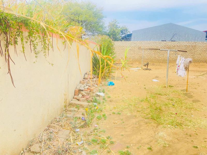 A rear yard area featuring a perimeter wall with security razor wire and a fixed washing line, requiring landscaping and maintenance.