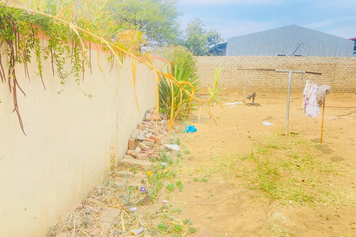 A rear yard area featuring a perimeter wall with security razor wire and a fixed washing line, requiring landscaping and maintenance.