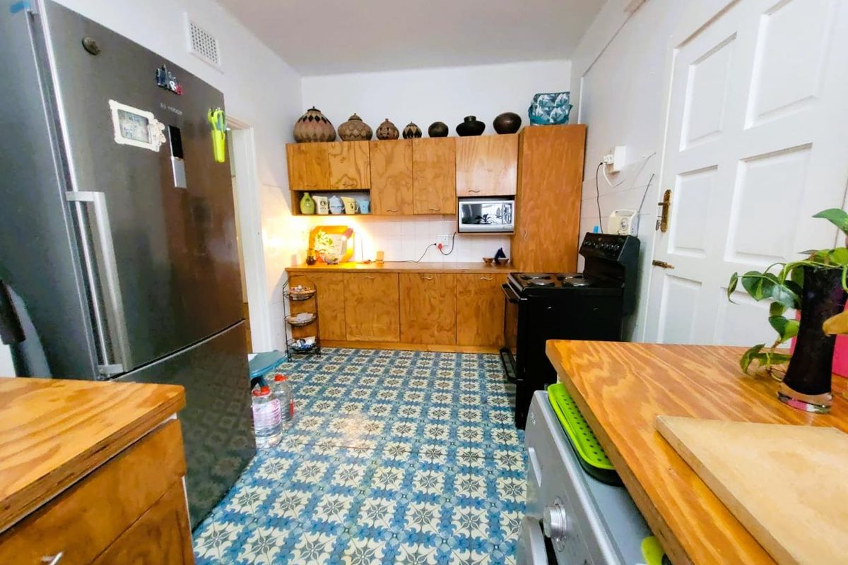 A functional kitchen featuring wooden cabinetry, patterned floor tiles, and a built-in oven, offering a classic aesthetic with potential for modern updates.