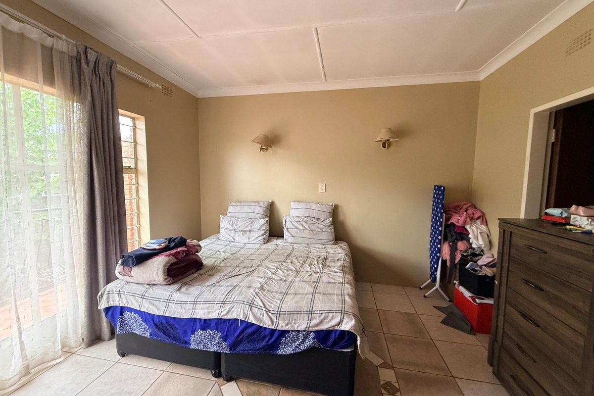 A bedroom featuring tiled flooring, wall-mounted lighting, and a sliding glass door providing access to an outdoor area.