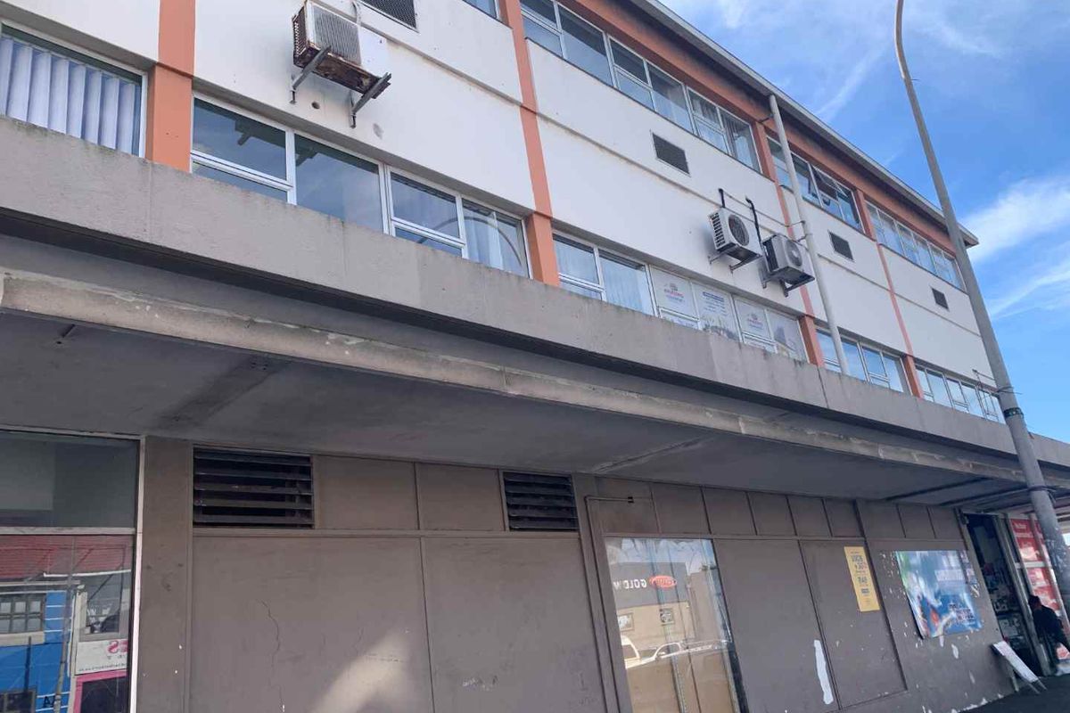 Exterior view of a multi-story office building featuring large windows, mounted air conditioning units, and a concrete facade with visible signs of wear.