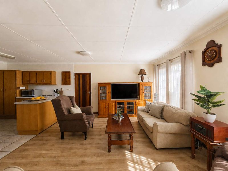 Open-plan living area featuring a functional kitchen with built-in cabinetry, a peninsula, and durable laminate flooring throughout the main living space.