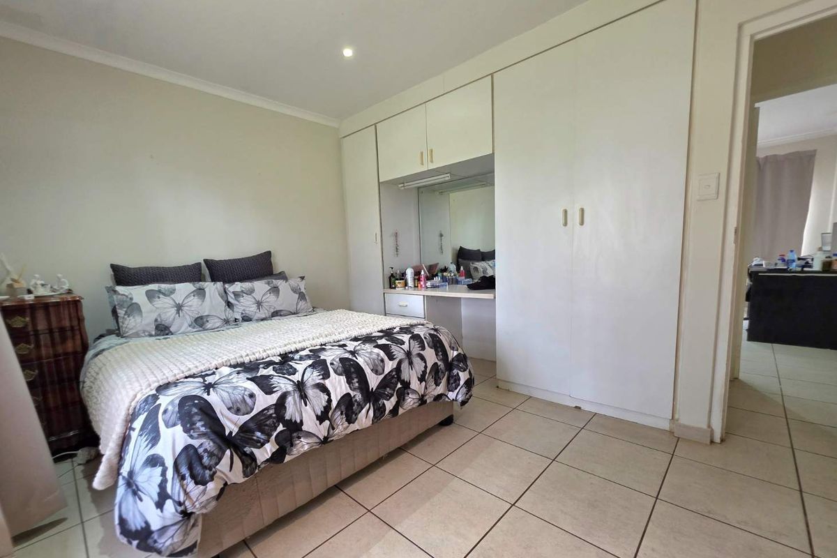 A bedroom featuring tiled flooring, built-in cupboards, and an integrated vanity area with a mirror.