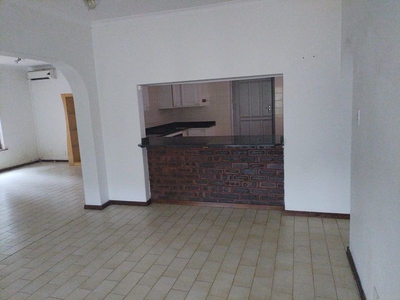 Open plan living area featuring a brick breakfast bar with granite countertop, ceramic tiled flooring, and an arched entryway leading to adjacent space.