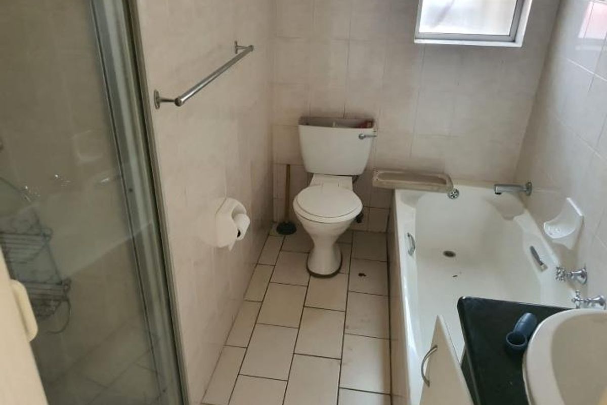 A functional bathroom featuring a separate shower enclosure, a standard bathtub, a toilet, and a vanity basin with tiled walls and flooring.