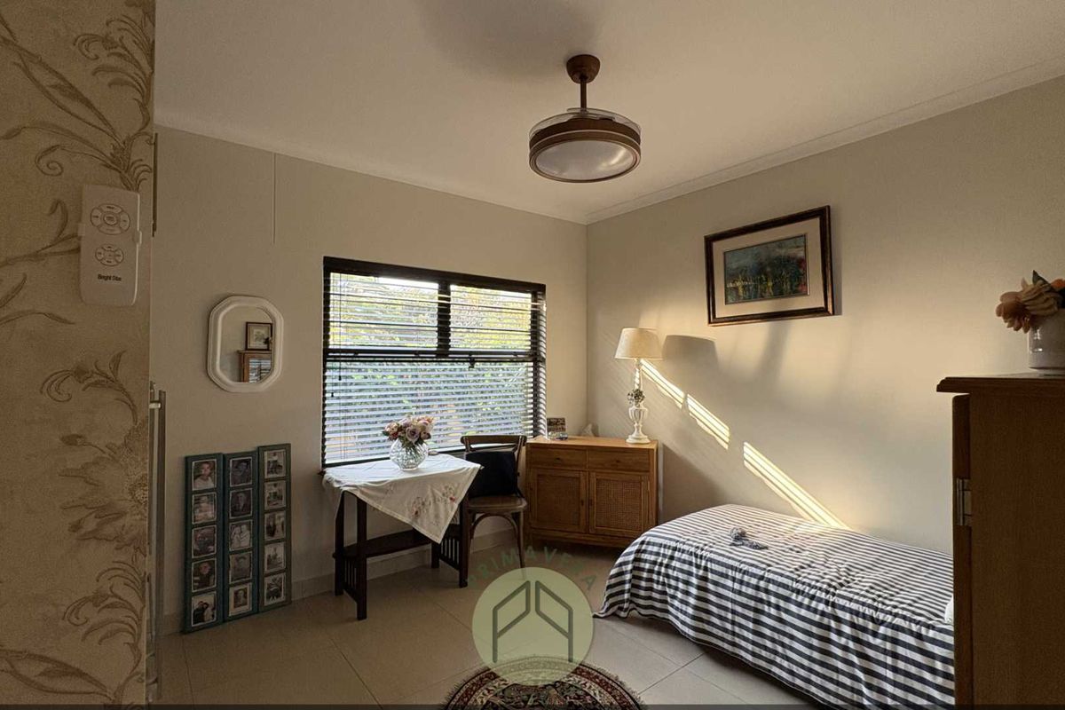 A functional bedroom featuring tiled flooring, a ceiling fan, and natural light through venetian blinds.