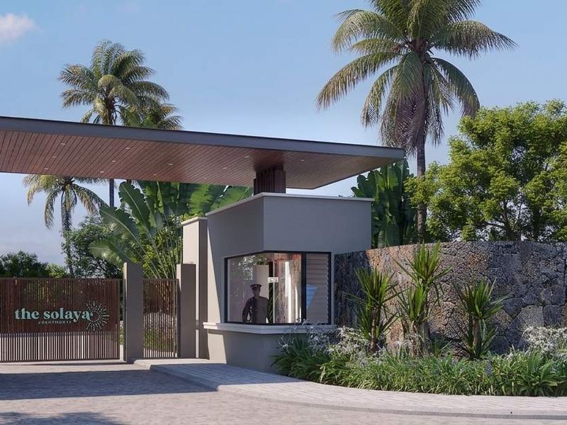 The main entrance to The Solaya Apartments featuring a modern security gatehouse, stone-clad walls, and a timber-accented overhead canopy.