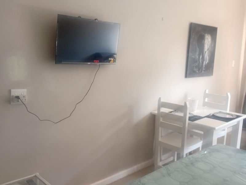 A bedroom featuring tiled flooring and neutral wall finishes, currently furnished with a bed and dining set.