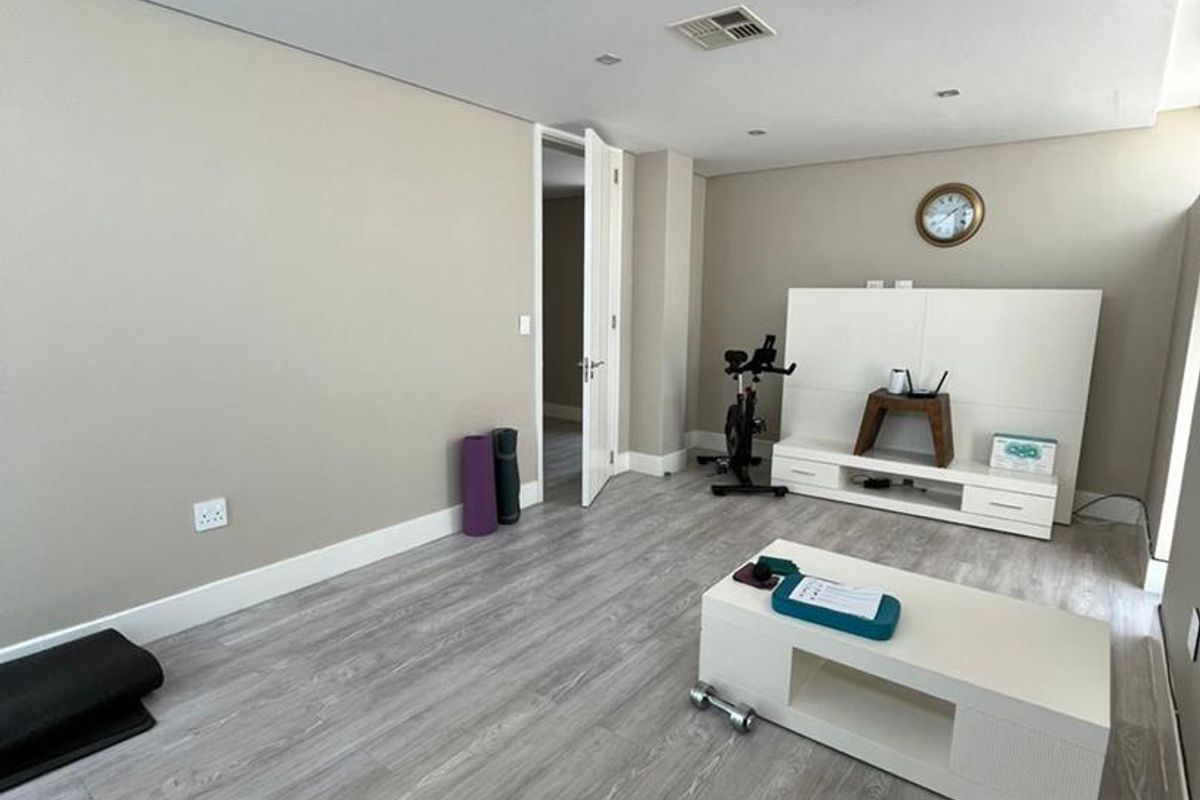 A spacious living area featuring modern laminate flooring, recessed ceiling lighting, and neutral wall tones, providing a versatile space for relaxation or home activities.