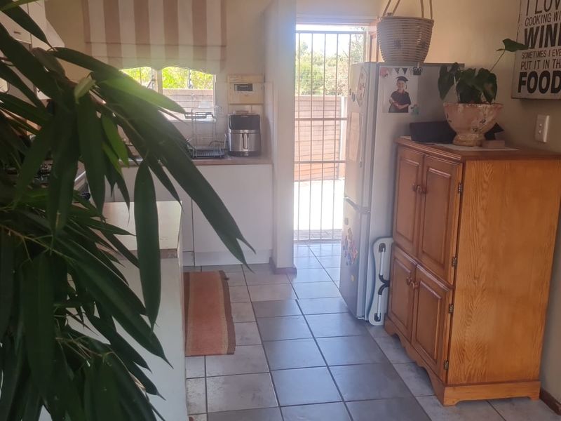 A functional kitchen area featuring tiled flooring, built-in cabinetry, and direct access to an outdoor space through a security gate.