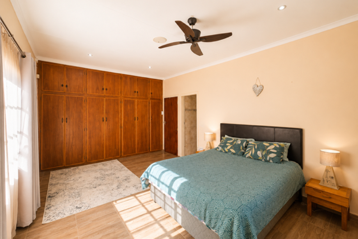 Spacious bedroom featuring extensive built-in wooden cabinetry, tiled flooring, and a ceiling fan, offering ample storage and a comfortable living environment.