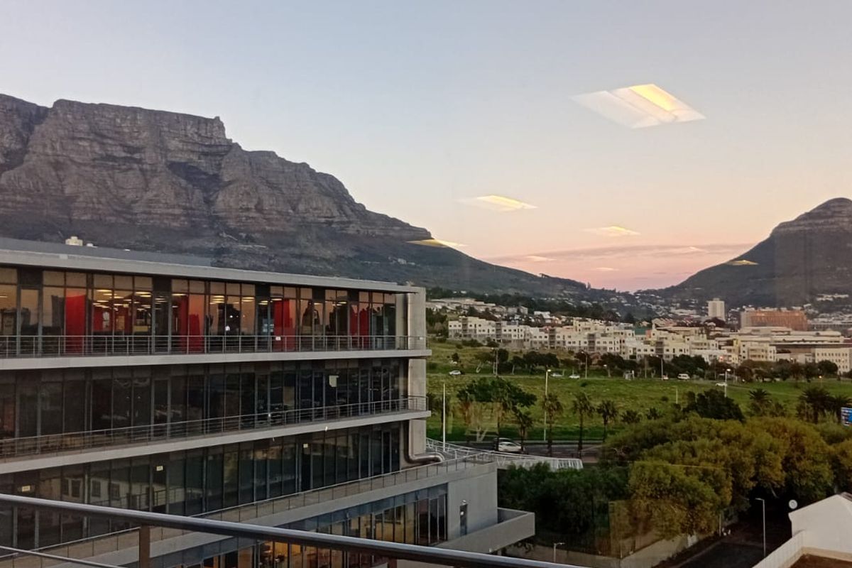 Elevated view of the office building exterior featuring modern glass facade architecture with scenic mountain and city landscape backdrop.