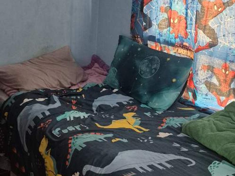 A bedroom featuring tiled flooring and blue wall paint, currently utilized as a child's room.