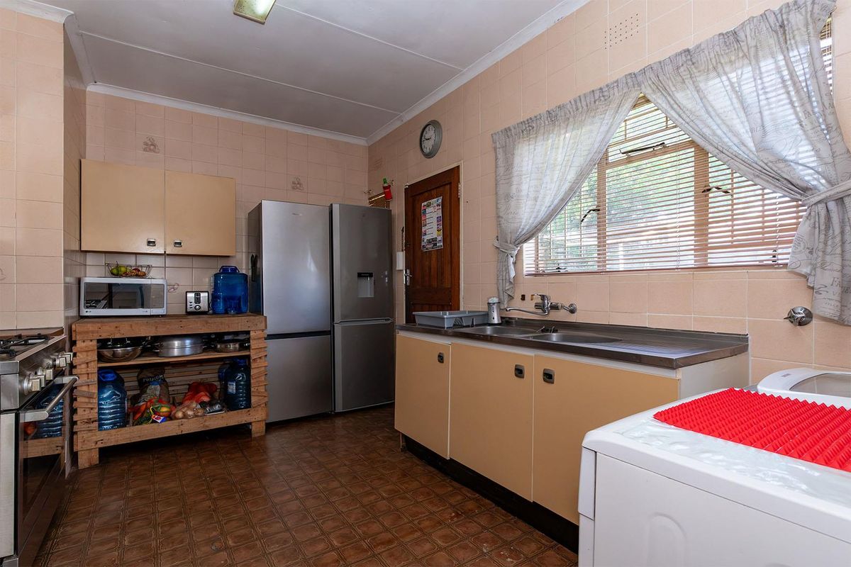 A functional kitchen featuring dated cabinetry, tiled splashbacks, a stainless steel sink, and a gas stove, offering potential for a modern renovation.