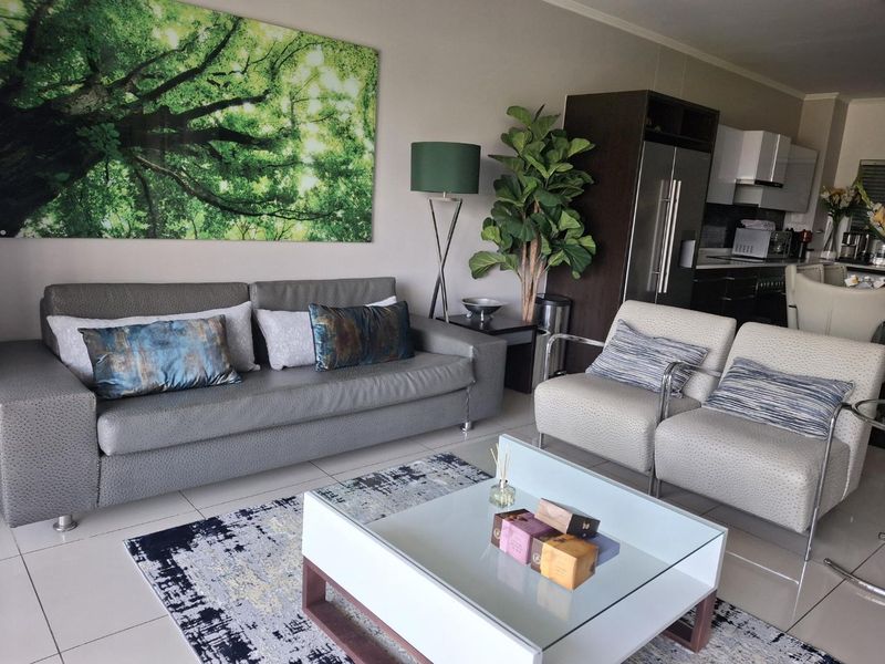 Open-plan living area featuring tiled flooring and a modern kitchen with integrated cabinetry, creating a cohesive and functional living space.