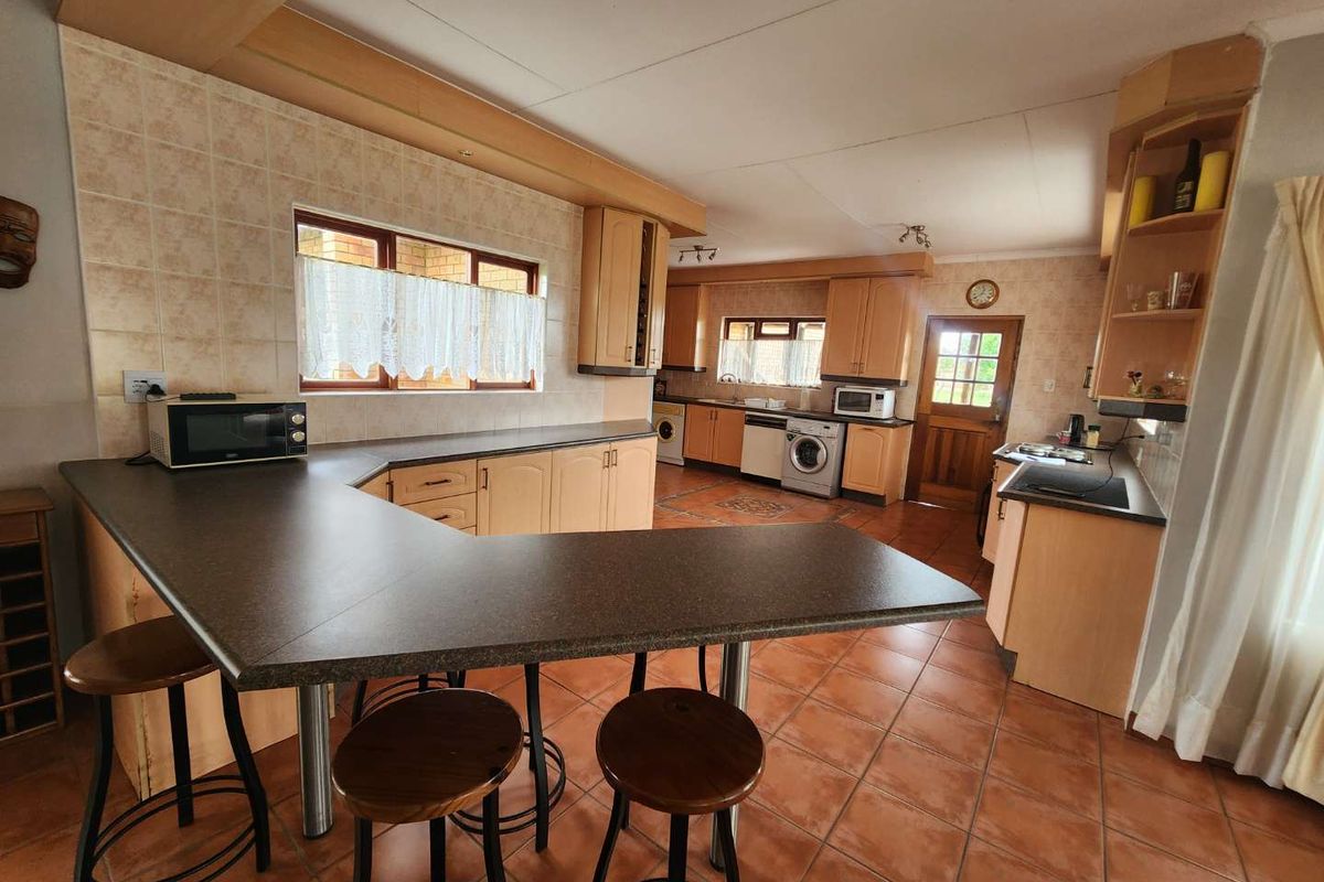 Spacious kitchen featuring laminate cabinetry, tiled flooring, a breakfast bar, and integrated appliances, offering a functional layout with ample counter space.