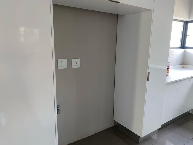 A clean, modern kitchen alcove featuring built-in cabinetry, tiled flooring, and dedicated electrical points, providing a functional space for appliances.