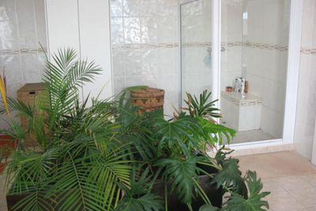 A bathroom featuring a built-in shower enclosure with glass doors, tiled walls, and tiled flooring, complemented by built-in cabinetry.