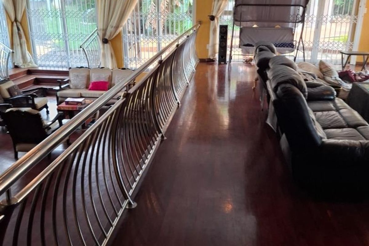 Spacious living area featuring polished hardwood flooring, a decorative metal balustrade, and large sliding glass doors leading to the exterior.