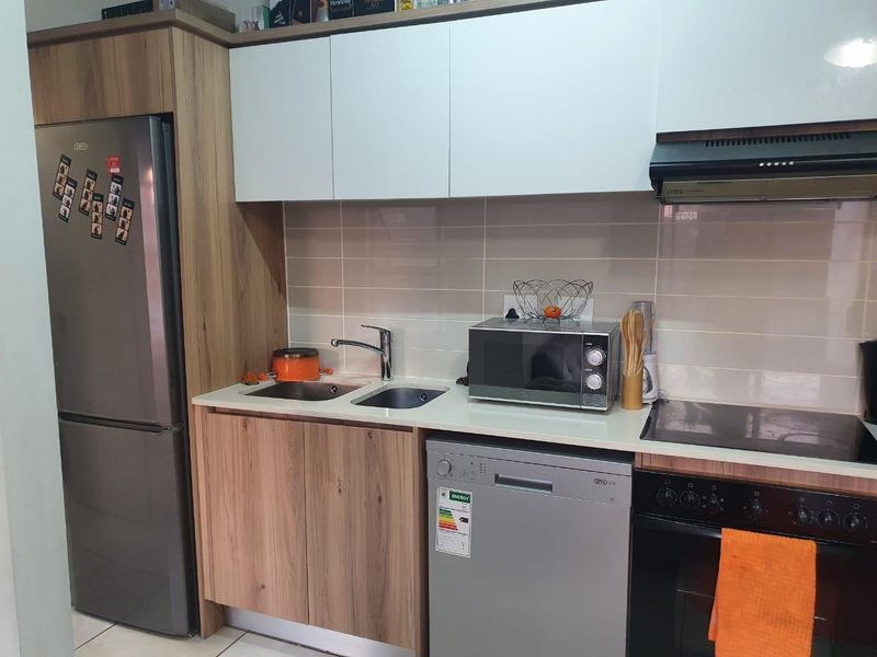 A modern kitchen featuring wood-grain and white cabinetry, stone countertops, a tiled backsplash, and integrated appliances including an oven, hob, and extractor fan.