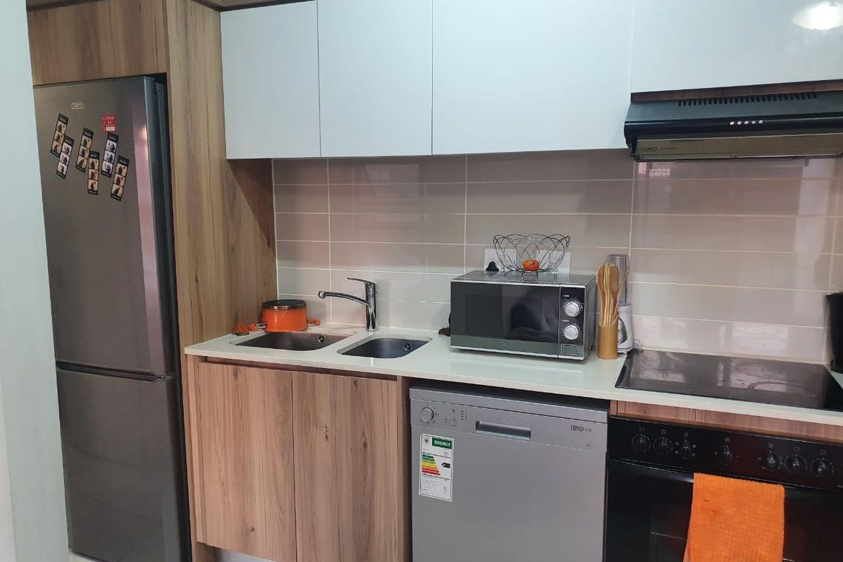 A modern kitchen featuring wood-grain and white cabinetry, stone countertops, a tiled backsplash, and integrated appliances including an oven, hob, and extractor fan.