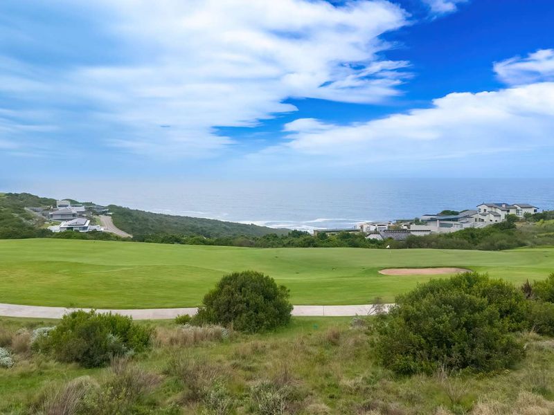 A scenic elevated view overlooking a manicured golf course with the ocean in the background.