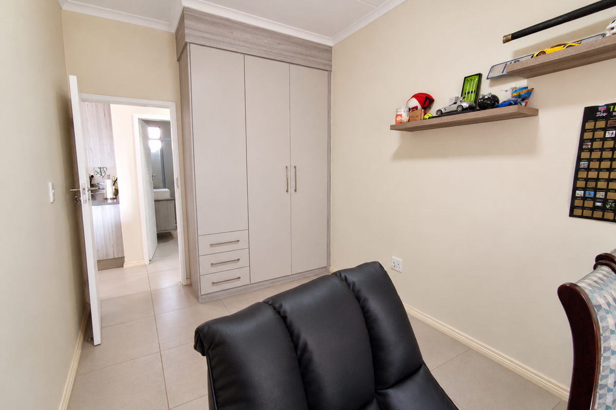 A well-maintained bedroom featuring neutral walls, tiled flooring, and a modern built-in wardrobe with integrated drawers.