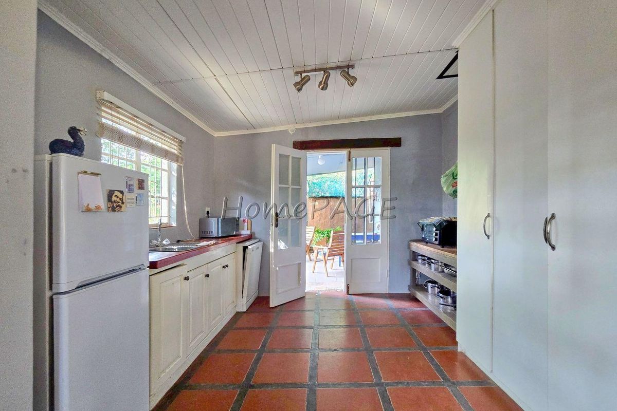 A functional kitchen featuring tiled flooring, white cabinetry, and direct access to an outdoor patio area through double doors.