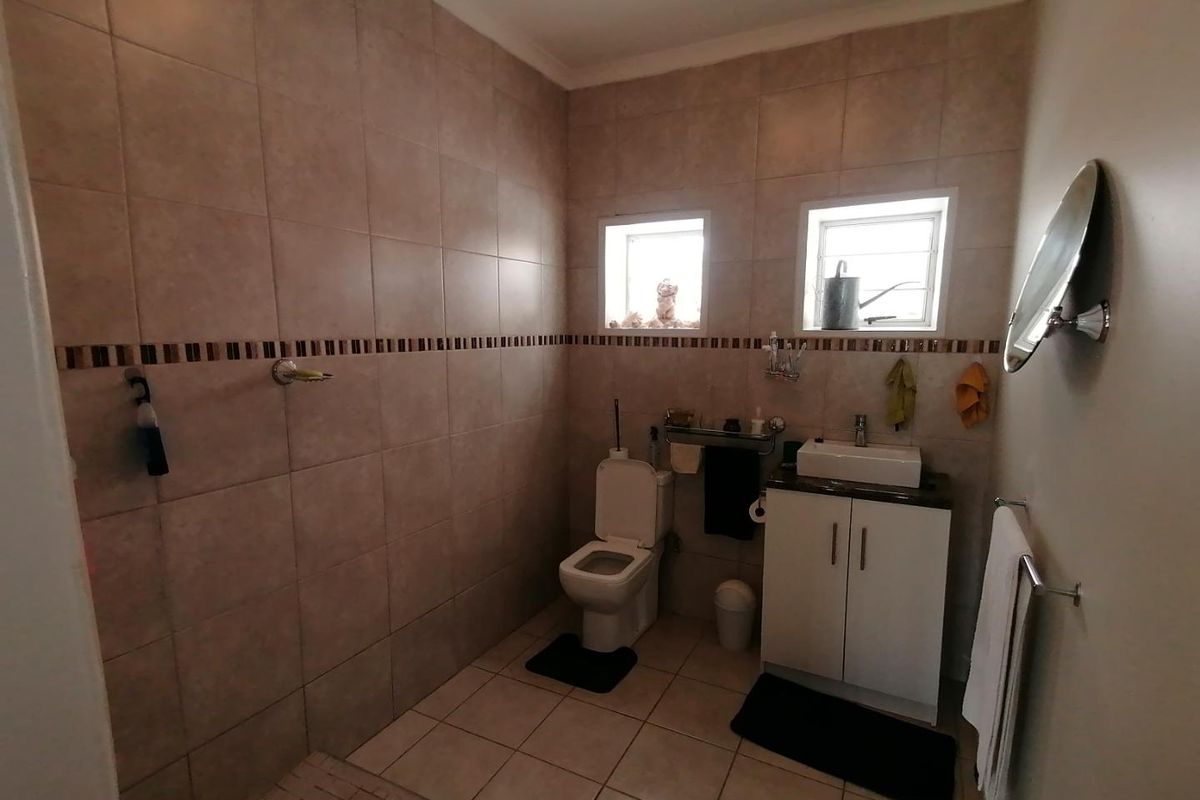 A functional bathroom featuring tiled walls and flooring, a walk-in shower, a toilet, and a vanity cabinet with a basin.